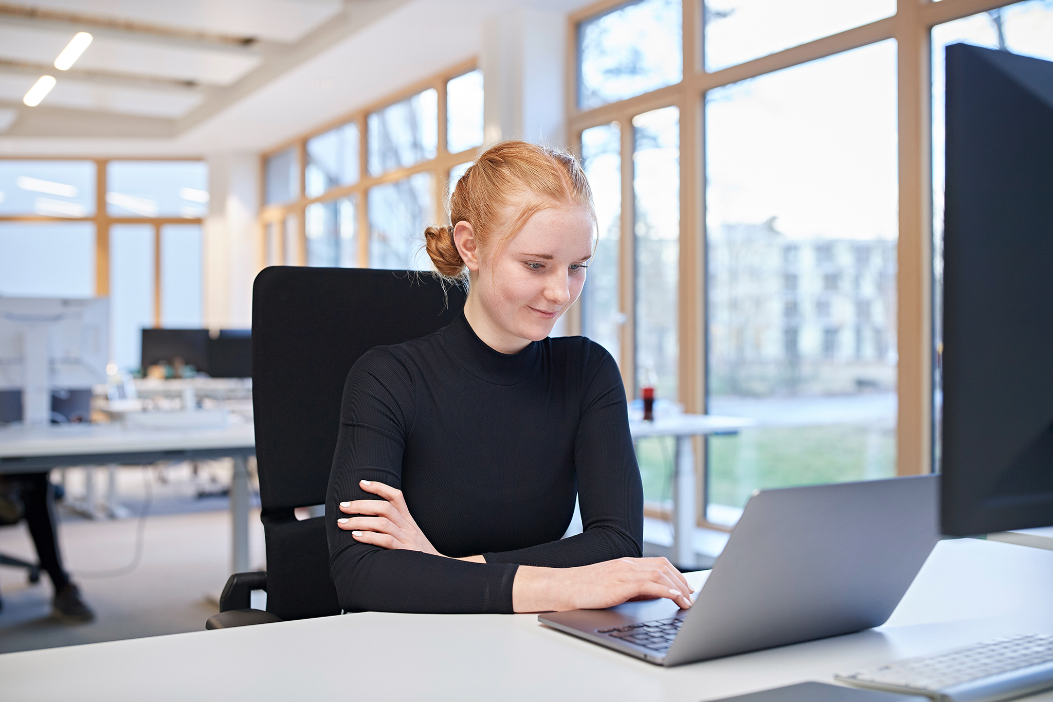 Mitarbeiterin sitzt in einer Agentur an einem Computer an einem Arbeitsplatz