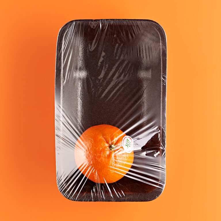 Fotografie Eduard Wellmann Orange in Plastik-Verpackung