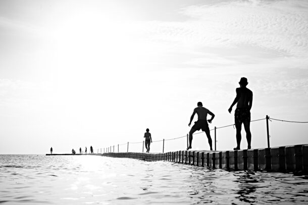 Menschen laufen auf einem Steg in Meer hinaus